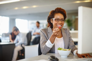 young businesswoman eating salad during her lunch at desk